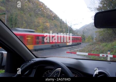 A car waits at railroad level crossing for the train to pass and crossing bar to lift. Stock Photo