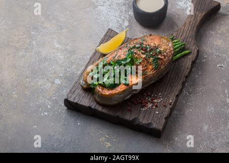 Fried salmon steak with vegetables on wooden board, copy space Stock Photo