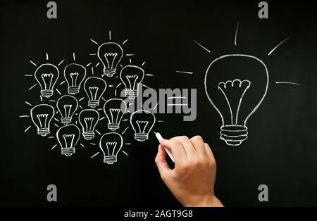 Hand drawing with chalk on blackboard light bulbs concept illustrating how a business team is working together creating a great idea. Many small ideas Stock Photo