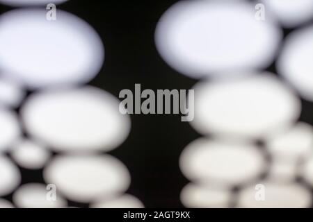blurred photo of white lights on a black background. dark spot in the middle Stock Photo