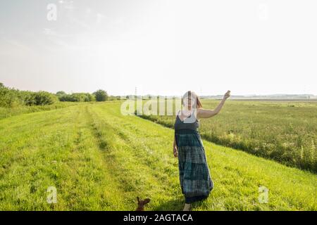 June 26, 2019 – Gainsborough, Lincolnshire, United Kingdom. An adult female stood on a grass riverbank holding her arm in the air. The weather is sunn Stock Photo