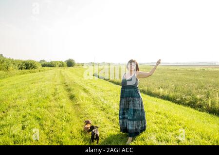 June 26, 2019 – Gainsborough, Lincolnshire, United Kingdom. An adult female stood on a grass riverbank holding her arm in the air. The weather is sunn Stock Photo