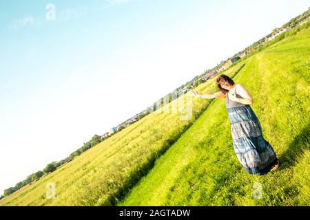 June 26, 2019 – Gainsborough, Lincolnshire, United Kingdom. An adult female stood on a grass riverbank holding her arm in the air. The weather is sunn Stock Photo