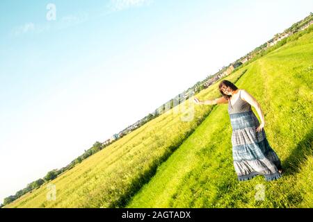 June 26, 2019 – Gainsborough, Lincolnshire, United Kingdom. An adult female stood on a grass riverbank holding her arm in the air. The weather is sunn Stock Photo