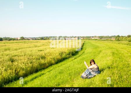 June 26, 2019 – Gainsborough, Lincolnshire, United Kingdom. An adult female stood on a grass riverbank holding her arm in the air. The weather is sunn Stock Photo