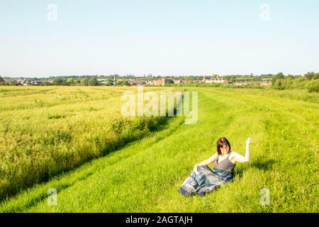 June 26, 2019 – Gainsborough, Lincolnshire, United Kingdom. An adult female stood on a grass riverbank holding her arm in the air. The weather is sunn Stock Photo