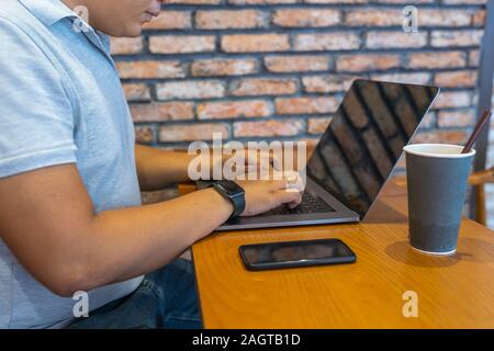 Asian businessman using laptop and smartphone at coffee table  Stock Photo