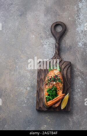 Fried salmon steak with vegetables on wooden board, copy space Stock Photo