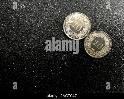 Two Swiss coins of twenty rappen on a black glittering background for new year 2020 with space for text. Stock Photo