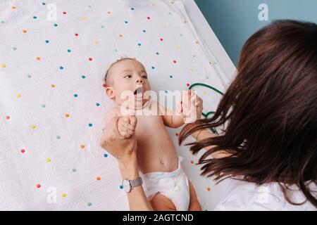 pediatrician doctor checks the baby's grasping reflexes Stock Photo