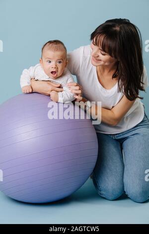 Young mother is engaged in exercises with her infant son Stock Photo