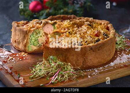 French quiches pie with broccoli,cheese and salmon. Salmon pie, Christmas decorated setting. Stock Photo