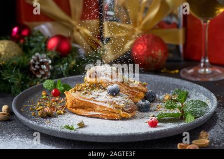 Traditional french dessert. Eclair with pistachios and custard. Dark background, Christmas decorated setting. Stock Photo