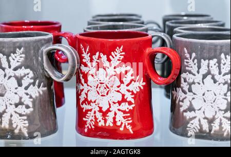 Red ceramic mug with a snowflake. Mugs on a store counter. Stock Photo
