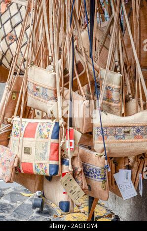 Ribeira Brava, Madeira, Portugal - Sep 9, 2019: Cork bags in the souvenir shops hanging on the street. Handmade cork products are traditional Portuguese souvenirs gifts. Stock Photo