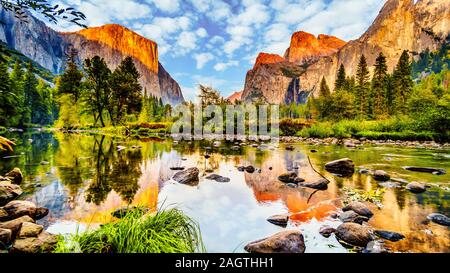 Sunset glow over El Capitan on the left and Cathedral Rocks, Sentinel Rock and Bridalveil Fall on the right and reflecting in the Merced River, CA Stock Photo
