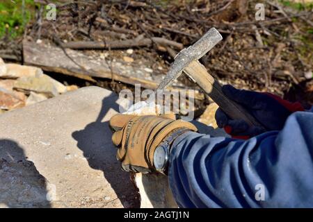 Craftsman preparing stone for dry stone wall with hammer, Matohanci near Pula, Croatia Stock Photo