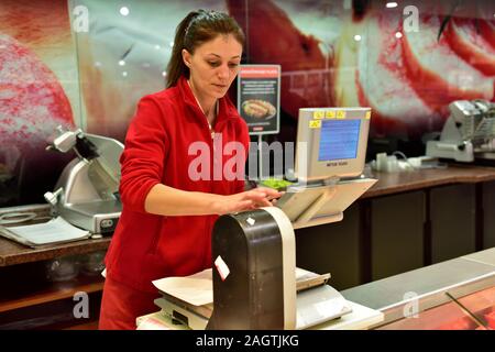 Woman weighing out meat at meat counter in Plodine supermarket, Bale, Croatia Stock Photo