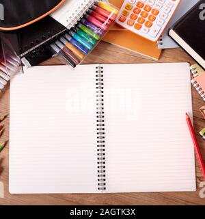 Busy student's desk with open notebook, school bag, text books and various pencils and crayons. Stock Photo