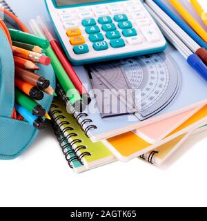 Various school supplies including notebooks, calculator and pencil case isolated against a white background Stock Photo