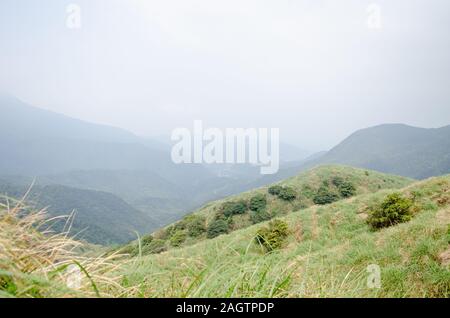 A hilly landscape with lush green grass at Yangmingshan National Park in Taiwan, March 2019 Stock Photo