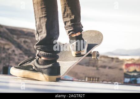 Close up view of teen's feet on a skateboard ready to start a ride over the half pipe. Skater starting jumps and tricks at the skate park. Let's go en Stock Photo