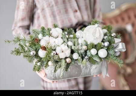 Arrangement of fresh spruce in a metal pot in womans hands. European Flowers shop. Christmas mood. Stock Photo