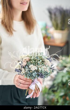 Colourful beautiful bouquet of mixed dried flowers in woman hand. the work of the florist at a flower shop. Stock Photo