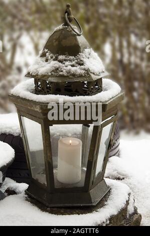 Upright burning Candle in a snow-covered lantern in the garden by jziprian Stock Photo