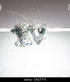 Three ice cubes that just fell into the water and leave a fountain Stock Photo