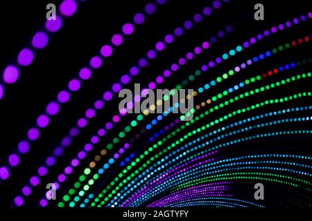 A tunnel of multi coloured lights lit up at night in an intentional out of focus shot to create circular strings of bokeh. Stock Photo