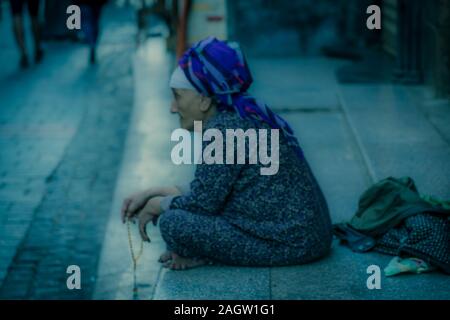 November 2019, LUXOR, EGYPT - older Moslem woman sits on street in poverty, Luxor Souq, Egypt Stock Photo