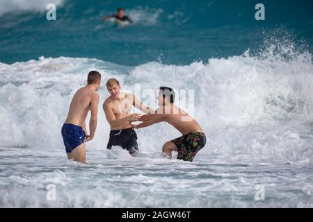 Palm Beach, Florida, USA. 21st Dec, 2019. SAM SPIEGEL, left, BAILEY SPIEGEL and DEOK JUN LEE, right, play in the rough surf in Palm Beach, Florida. A low-pressure system is developing in the Gulf of Mexico and could cause storms -- and even tornadoes -- in southern Florida starting Saturday. The National Weather Service in Miami is predicting severe storms, heavy rain and flooding through Sunday. Credit: Greg Lovett/ZUMA Wire/Alamy Live News Stock Photo