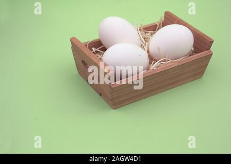 A box with three white eggs on a neutral green background Stock Photo