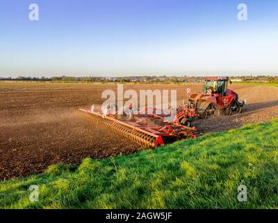 A lovely summer's evening on flat British countryside land, open fields with grass and ploughed land as the sun sets in the background. Stock Photo