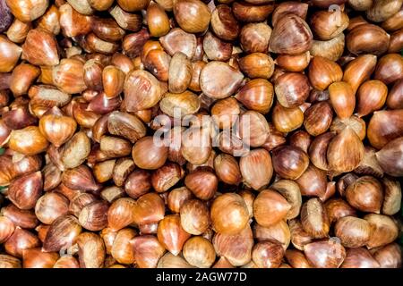 Piles of fresh unpeeled raw chestnuts. Stock Photo