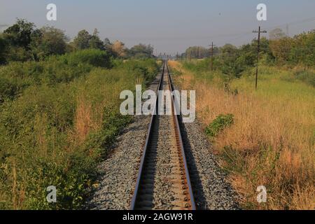 railway tracks. one point perspective view of a strait long train rail track. train path in a rural area. Stock Photo