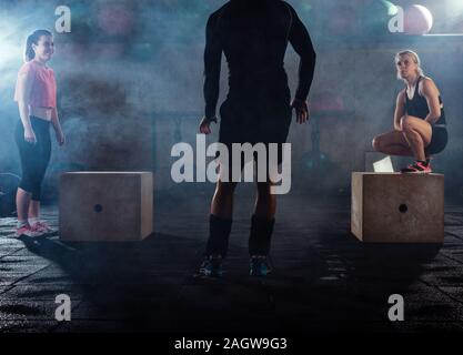 Trainer supervising muscular athletes doing jumping squats Stock Photo