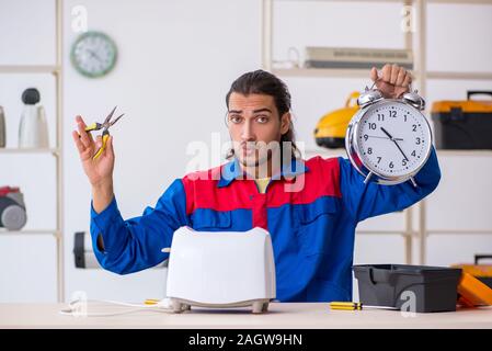 The young male contractor repairing toaster at workshop Stock Photo