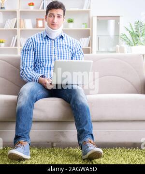 The man freelancer in a cervical collar neck brace working from home Stock Photo