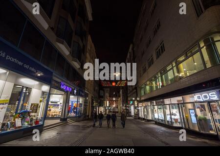 BRNO, CZECHIA - NOVEMBER 5, 2019: Youngsters, czech teenagers, walking in a deserted pedestrian street of Brno, Ceska Ulice, at night, surrounded by c Stock Photo
