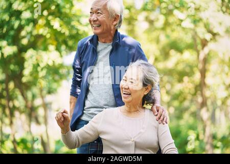 senior asian man and wheelchair bound woman relaxing outdoors in park Stock Photo