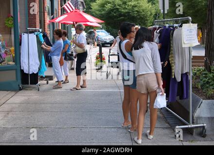 Middletown, CT USA. Jul 2015. Asian American teenagers going through some used clothing outdoors at small town Main Street. Stock Photo