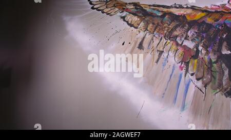 Artist designer draws an eagle on the wall. Craftsman decorator paints picture with acrylic oil color. Painter painter dressed in paint coat. Indoor. Stock Photo