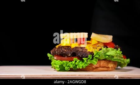 Craft burger is cooking. Consist: red sauce salsa, lettuce, red onion, pickle, cheese, chilli green pepper, air bun and marbled meat beef. Stock Photo