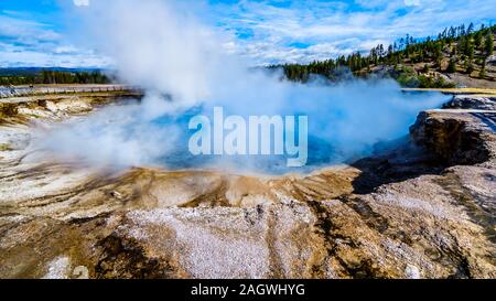 The blue-turquoise water of the Excelsior Geyser Crater in the Lower Geyser Basin at the Grand Prismatic Spring Trail in Yellowstone National Park, WY Stock Photo