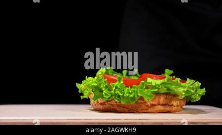 Craft burger is cooking. Consist: red sauce salsa, lettuce, red onion, pickle, cheese, chilli green pepper, air bun and marbled meat beef. Stock Photo