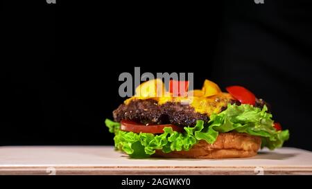 Craft burger is cooking. Consist: red sauce salsa, lettuce, red onion, pickle, cheese, chilli green pepper, air bun and marbled meat beef. Stock Photo