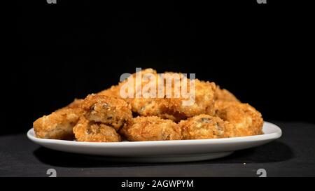 Cool beautiful fresh juicy cooked chicken wings in breading. Buffalo wings spread on food in white plate. Cooking with deep fryer fry machine. Stock Photo