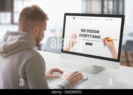 Web design studio with concept agency web page on computer display. Guy work on computer. Office interior Stock Photo